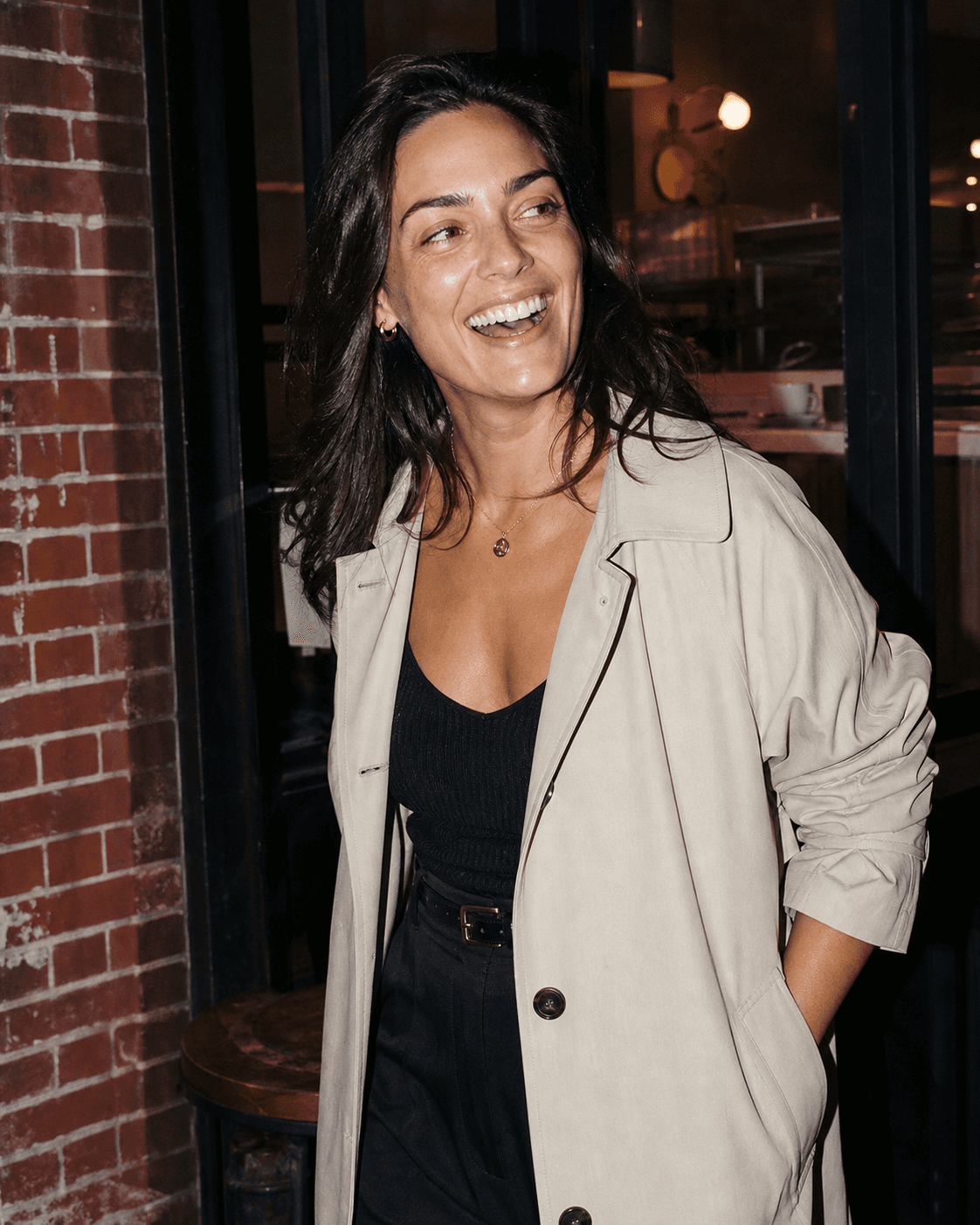 A single woman laughing outside a café at night